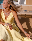 Woman in a yellow dress sitting on a boat with a scenic background and she is wearing sterling silver jewelry