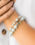 Close-up of a wrist wearing a light blue and green beaded bracelet on a white background