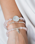 Stack of pink beaded bracelets on a wrist with a plain white background