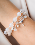 Bracelet with white beads and a palm tree charm on a wrist.