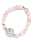 Pink beaded bracelet with a silver charm on a white background