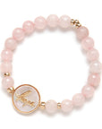 Pink beaded bracelet with a gold charm on a white background