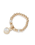 Gold elastic ring with pearls and a moonstone charm on a white background