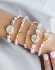 Three pearl and gold bracelets on a person's wrist against a white background