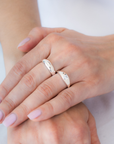 Close-up of two hands with silver rings on a neutral background