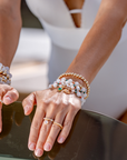 Close-up of hands wearing multiple bracelets and rings on a boat.