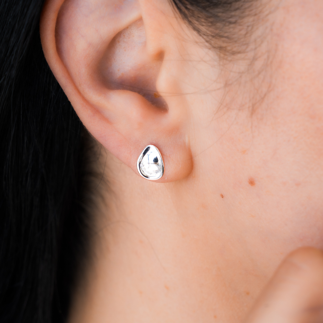 Close-up of an ear wearing a silver  pebble earring 