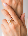Close-up of a hand wearing stacked elastic rings in white tones, set against a light gray background.
