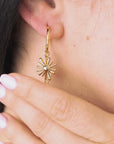 Video of a woman gently touching and showcasing her earrings, highlighting elegant pendant earrings featuring a sun charm and vibrant, colorful beads.