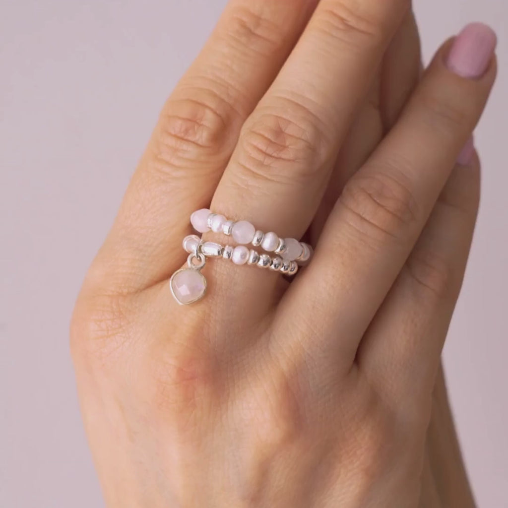 video of a Hand wearing multiple pearl rings on a neutral background