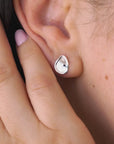 Woman is wearing a silver  pebble earrings.