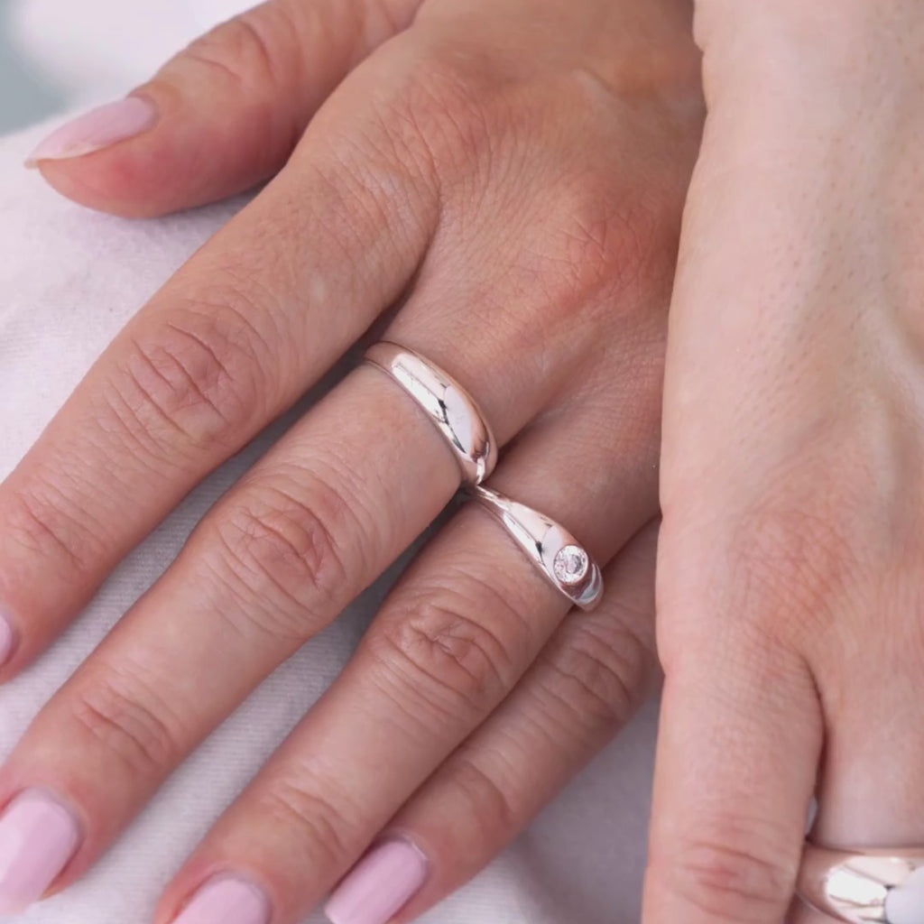 Close-up of a hand wearing two sterling silver rings on with a zircon.