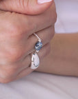 Hand wearing a stack of silver rings, including a blue sodalite elastic ring, on a white shirt. / beblue bijoux