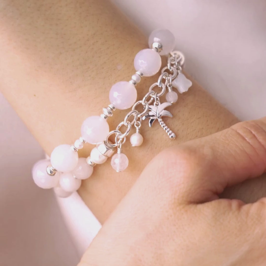 video of Bracelet with white beads and a palm tree charm on a wrist.