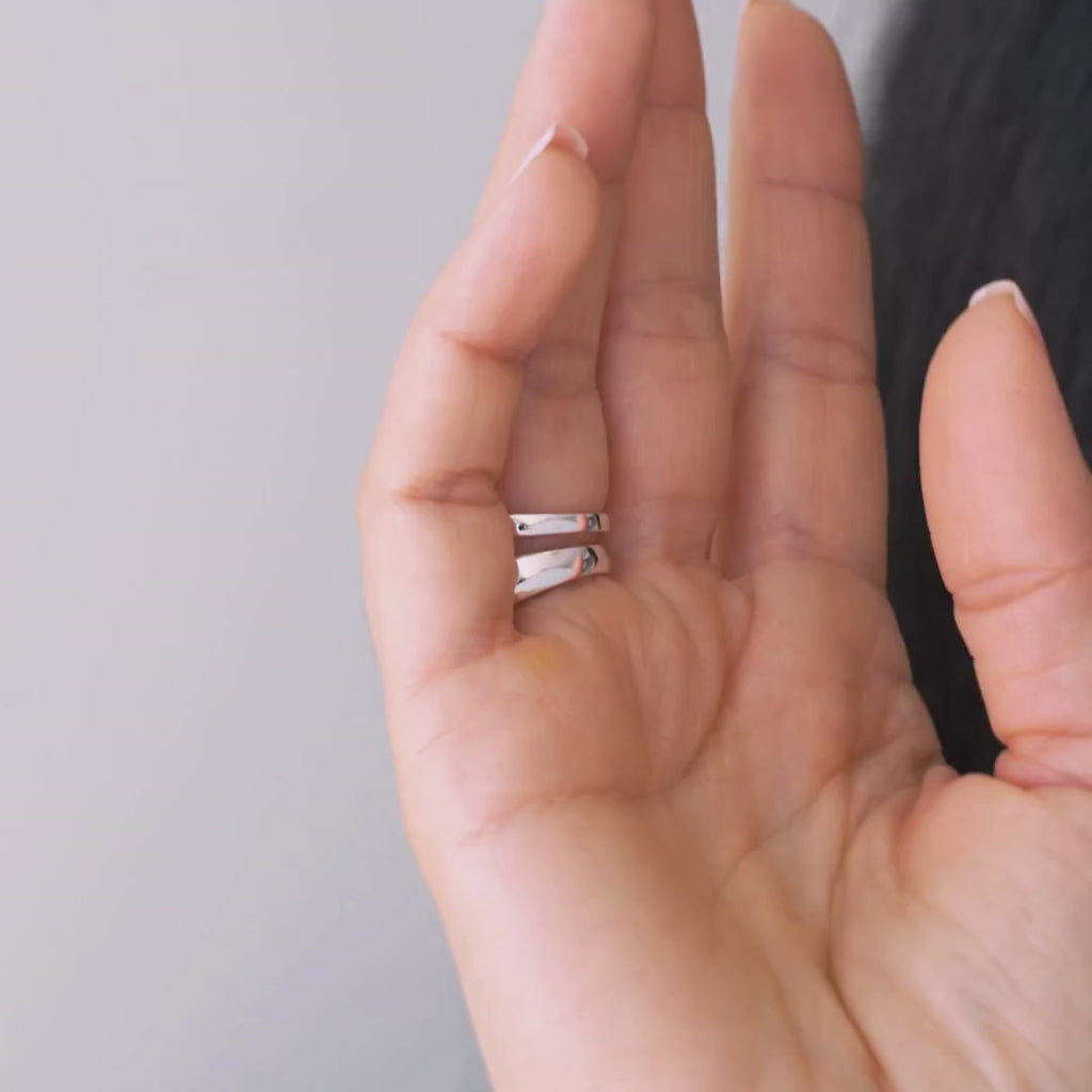 Close-up of a hand wearing two sterling silver rings; one is voluptuous and pairs perfectly with a smaller one, creating the perfect duo.