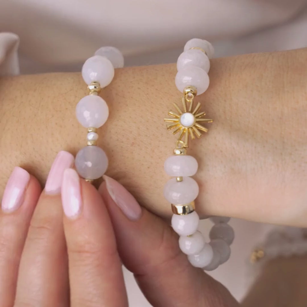 Video of a woman wearing a white bracelet with a sun charm.
