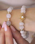 Video of a woman wearing a white bracelet with a sun charm.
