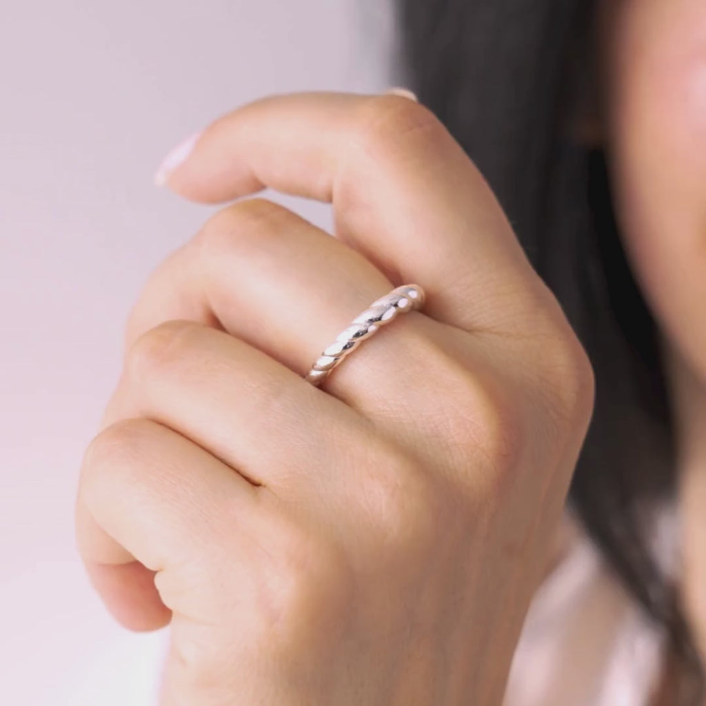 Close-up of a hand wearing a silver ring with a blurred background