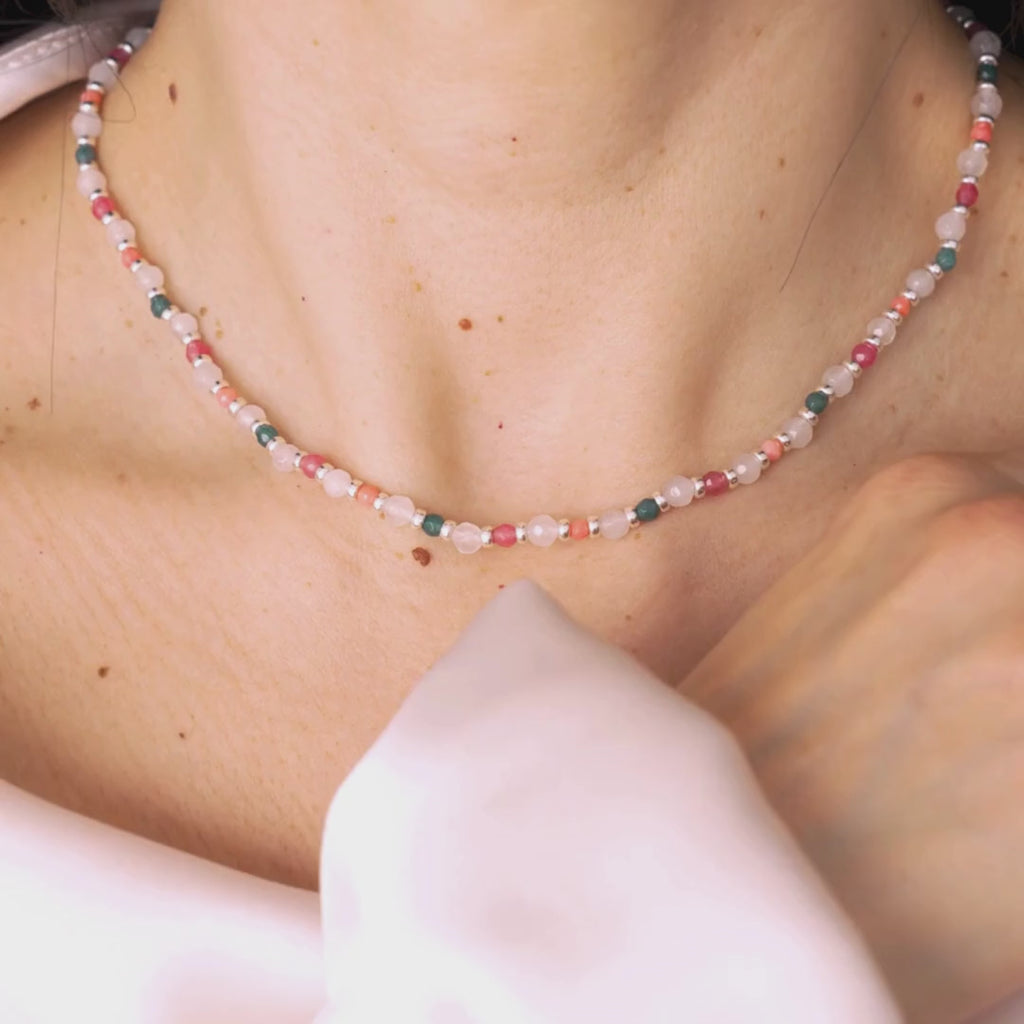 video of Close-up of a person wearing delicate necklace made of white agate with touches of color set in sterling silver.
