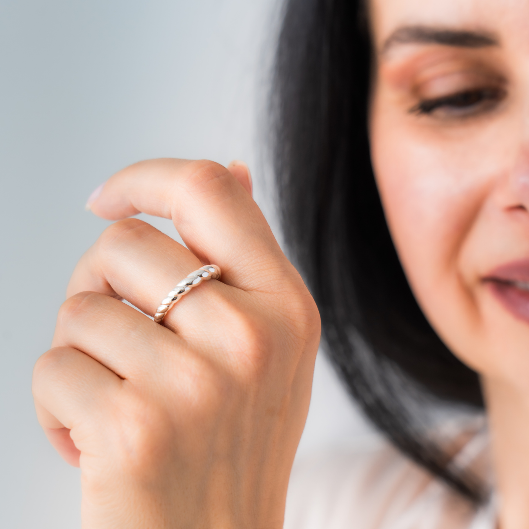 Close-up of a hand wearing a silver ring with a blurred background